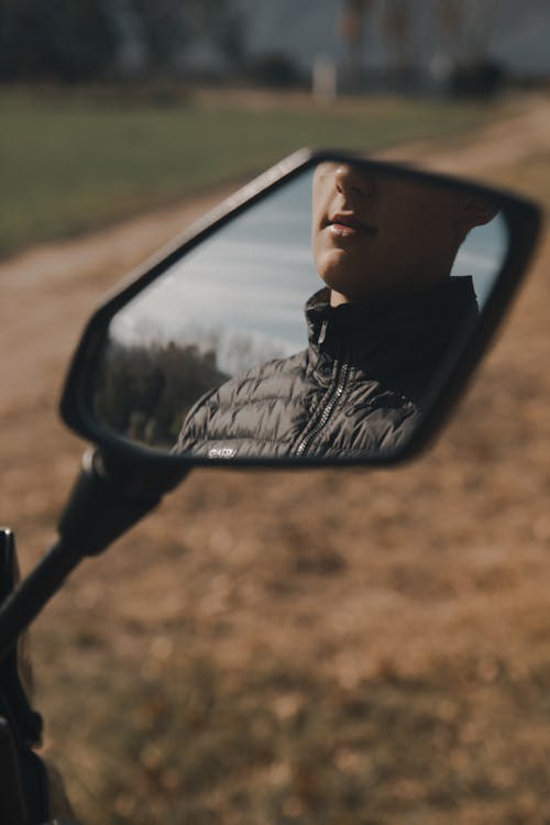 A Reflection of a Person on a Motorcycle Side Mirror