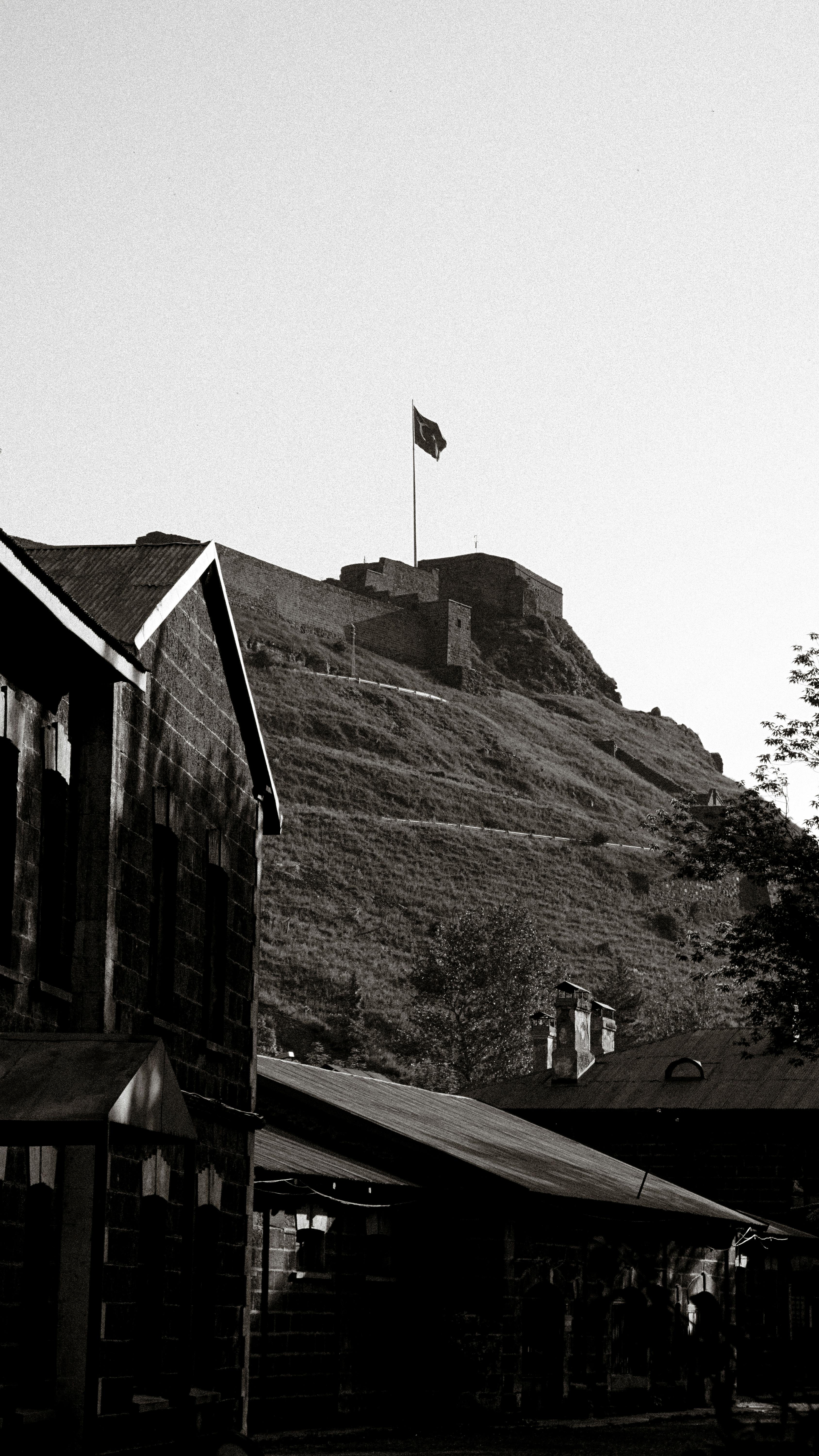 Black and white photo of a historic castle on a hill with a flag in Turkey.
