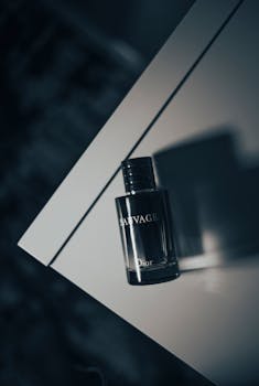 A stylish perfume bottle captured in a minimalist still life setting with a play of shadows on a white surface.