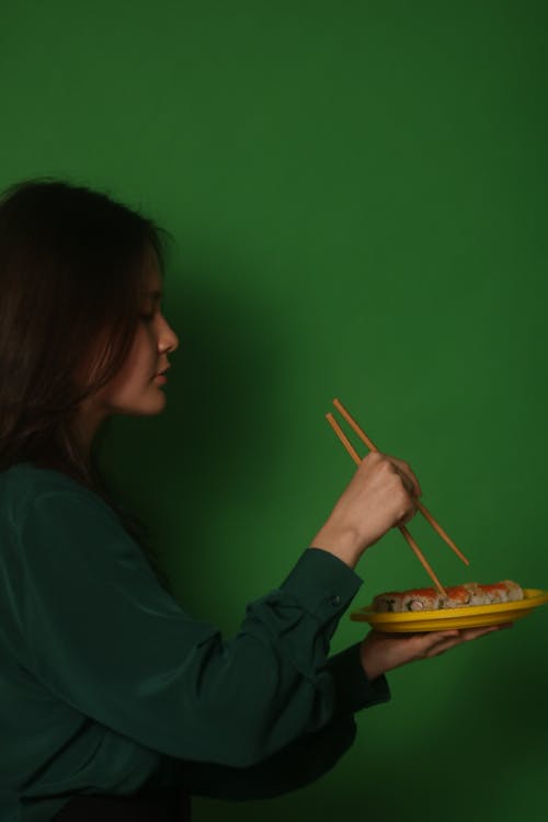 Side View of a Woman Getting Sushi Rolls with Chopsticks