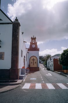 Picturesque church with a cross in a quaint Spanish town under a bright sky.