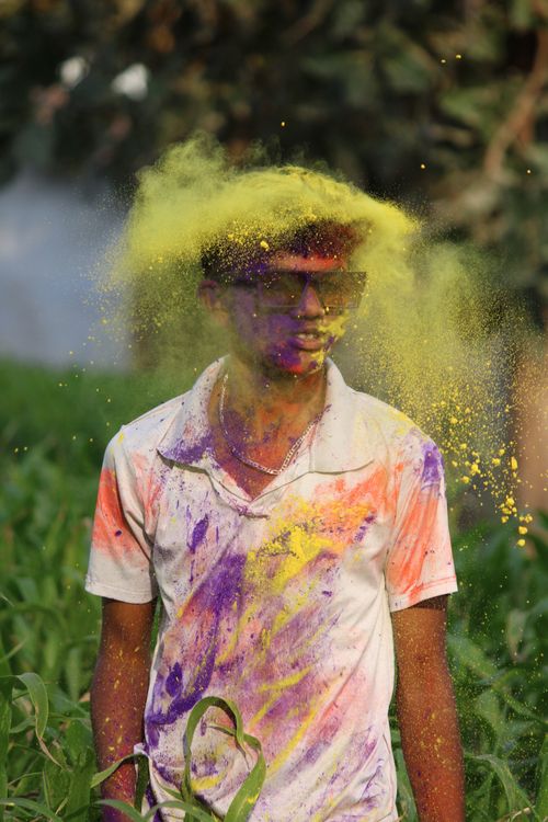 Free A young person enjoying the vibrant colors of Holi festival outdoors. Stock Photo