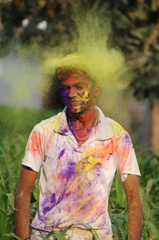 A man joyfully celebrating Holi outdoors, covered in colorful powder.