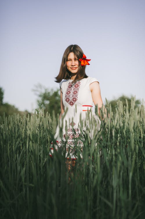 A Woman in White Dress Standing on Wheat Field while Smiling at the Camera