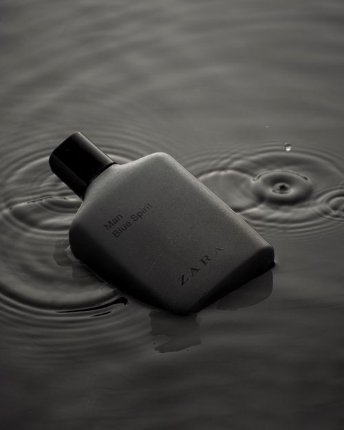 Free Product photo of a black Zara 'Blue Spirit' perfume bottle floating on water with ripples and reflections. Stock Photo
