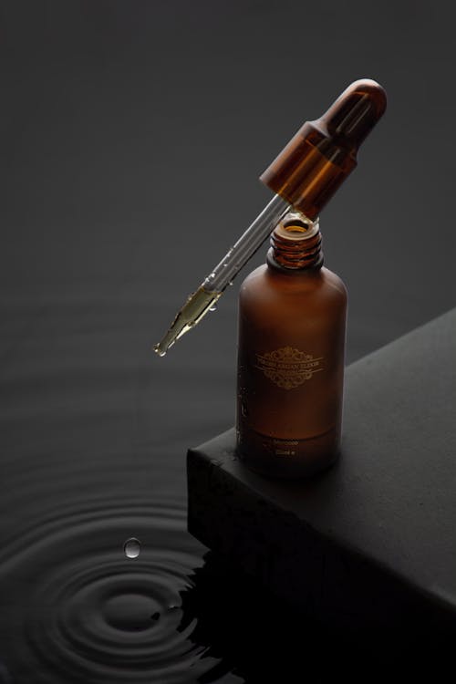 Free Brown and Silver Bottle on Black Surface Stock Photo