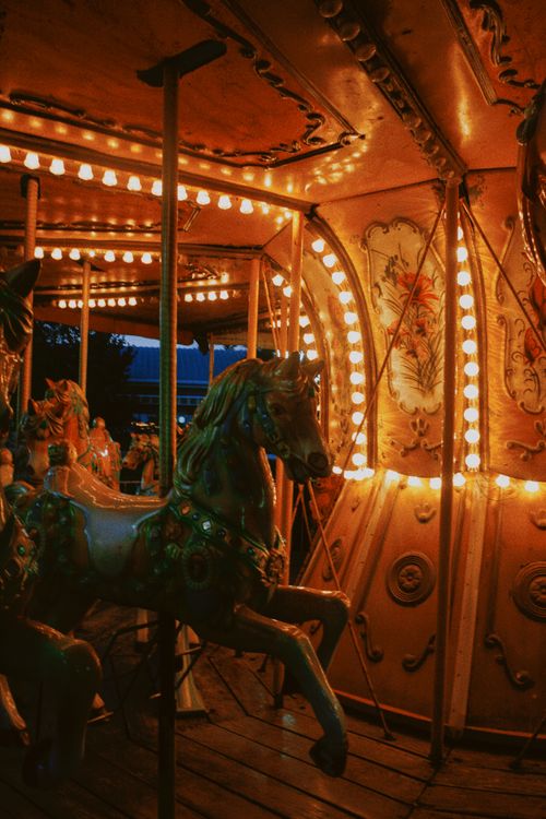 Free A beautifully lit carousel horse glowing warmly in the night at an amusement park. Stock Photo