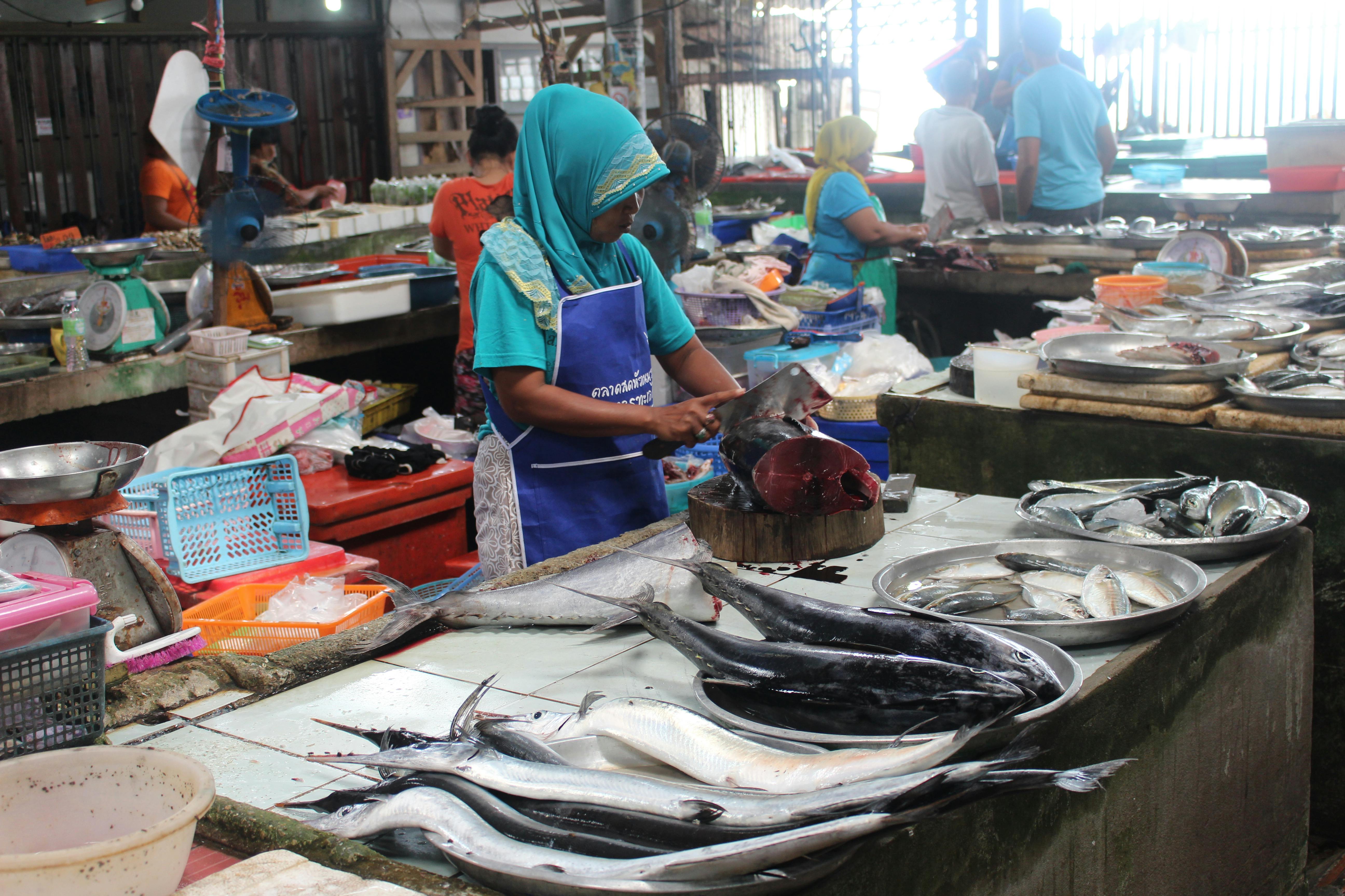 A woman in a headscarf preparing fresh seafood at a wet market in Koh Samui, Thailand. - Koh Samui
