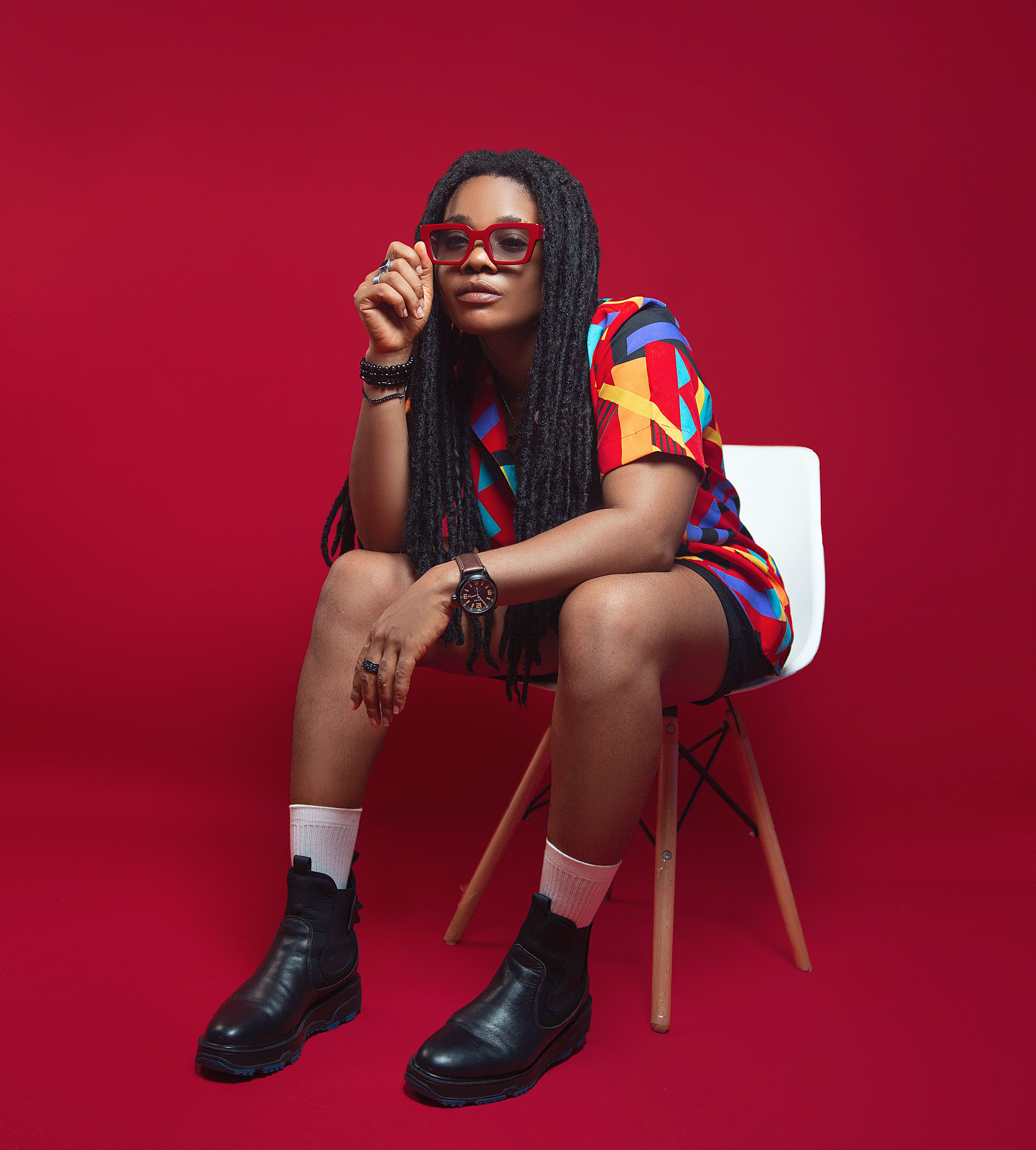 Portrait of a fashionable woman sitting on a chair in a vibrant studio setting.
