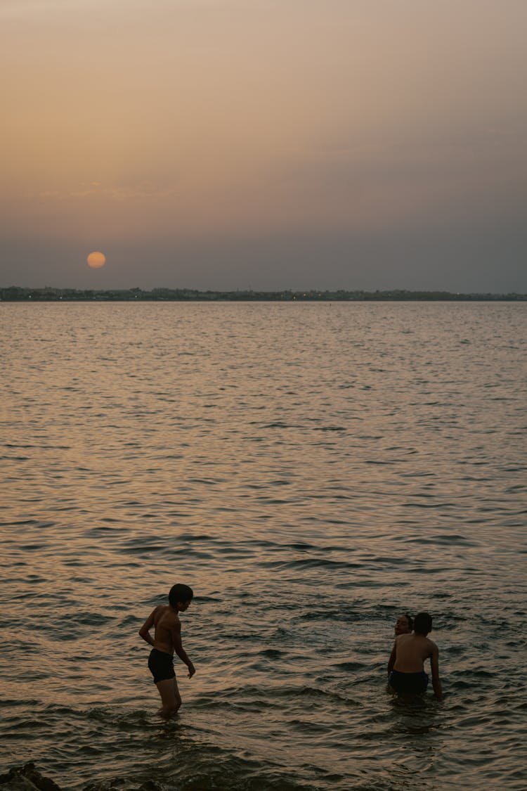 Kids Bathing In A Sea At Dusk