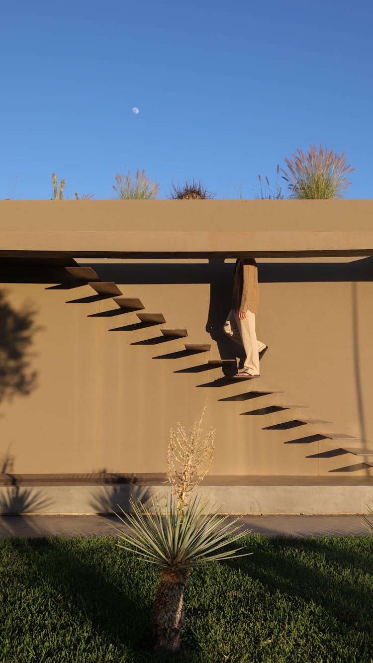 Man Walking Up The Outdoor Steps Of A Modern House 