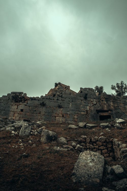 Free A dramatic view of a medieval castle ruin under a moody, overcast sky. Stock Photo