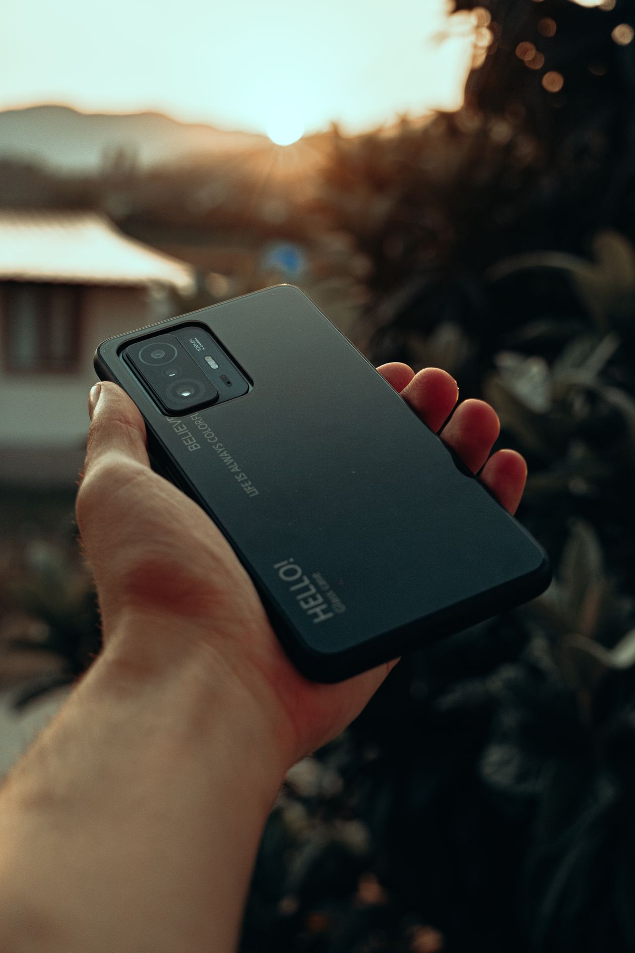 Close-up of a hand holding a smartphone outdoors at sunset