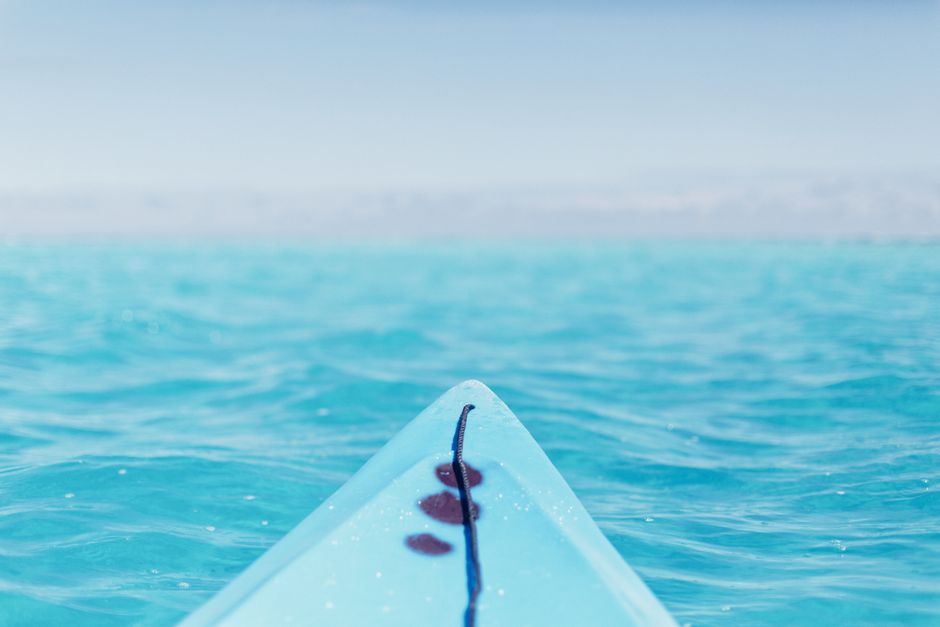 Experience tranquility with this close-up of a surfboard floating on calm, turquoise waters in French Polynesia.