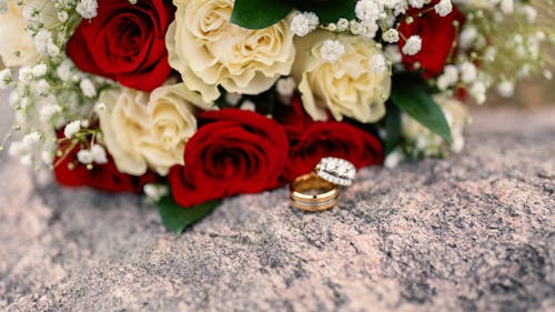 Wedding Rings next to Bouquet of Roses