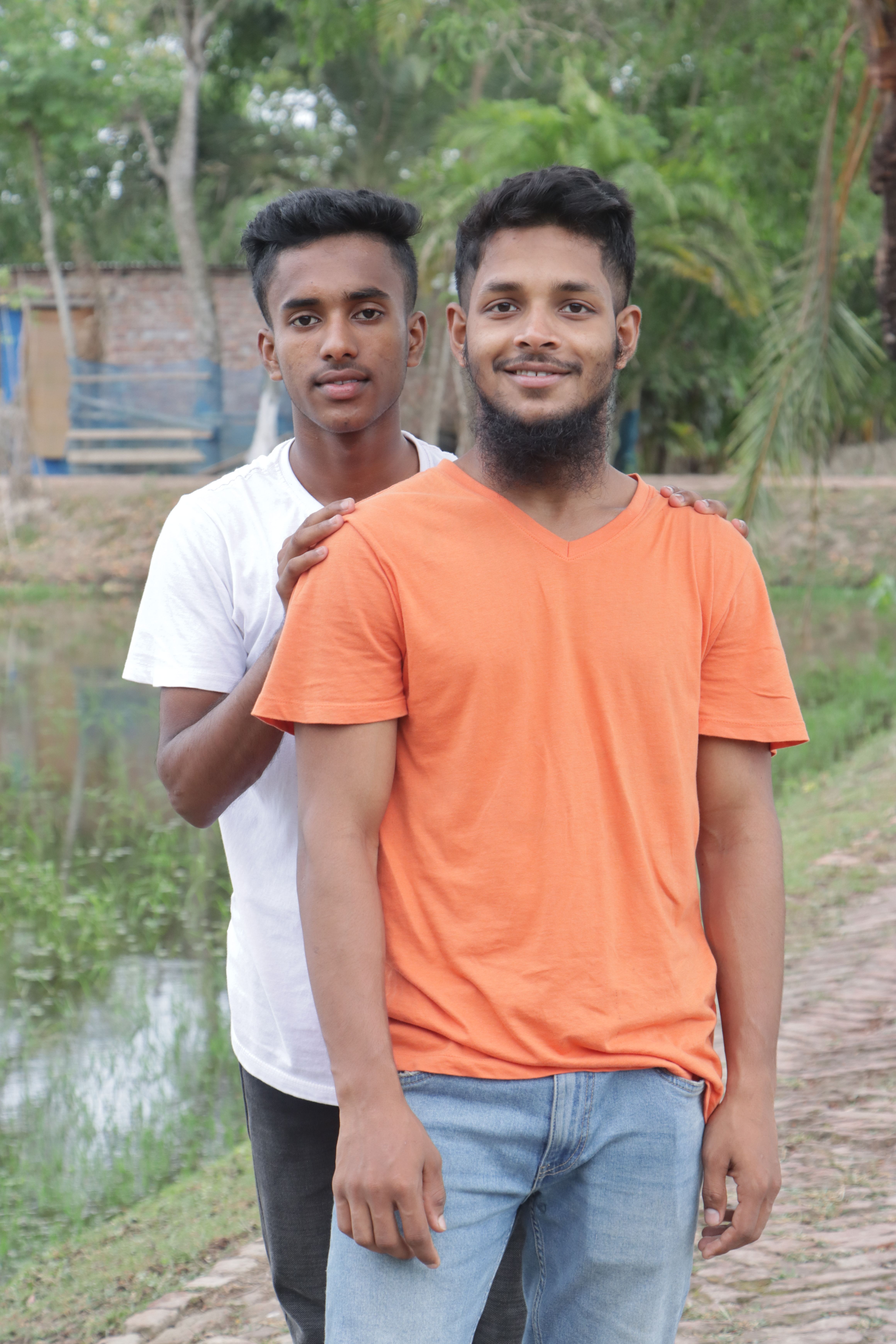 Two young men smiling in a serene outdoor setting, enjoying friendship.
