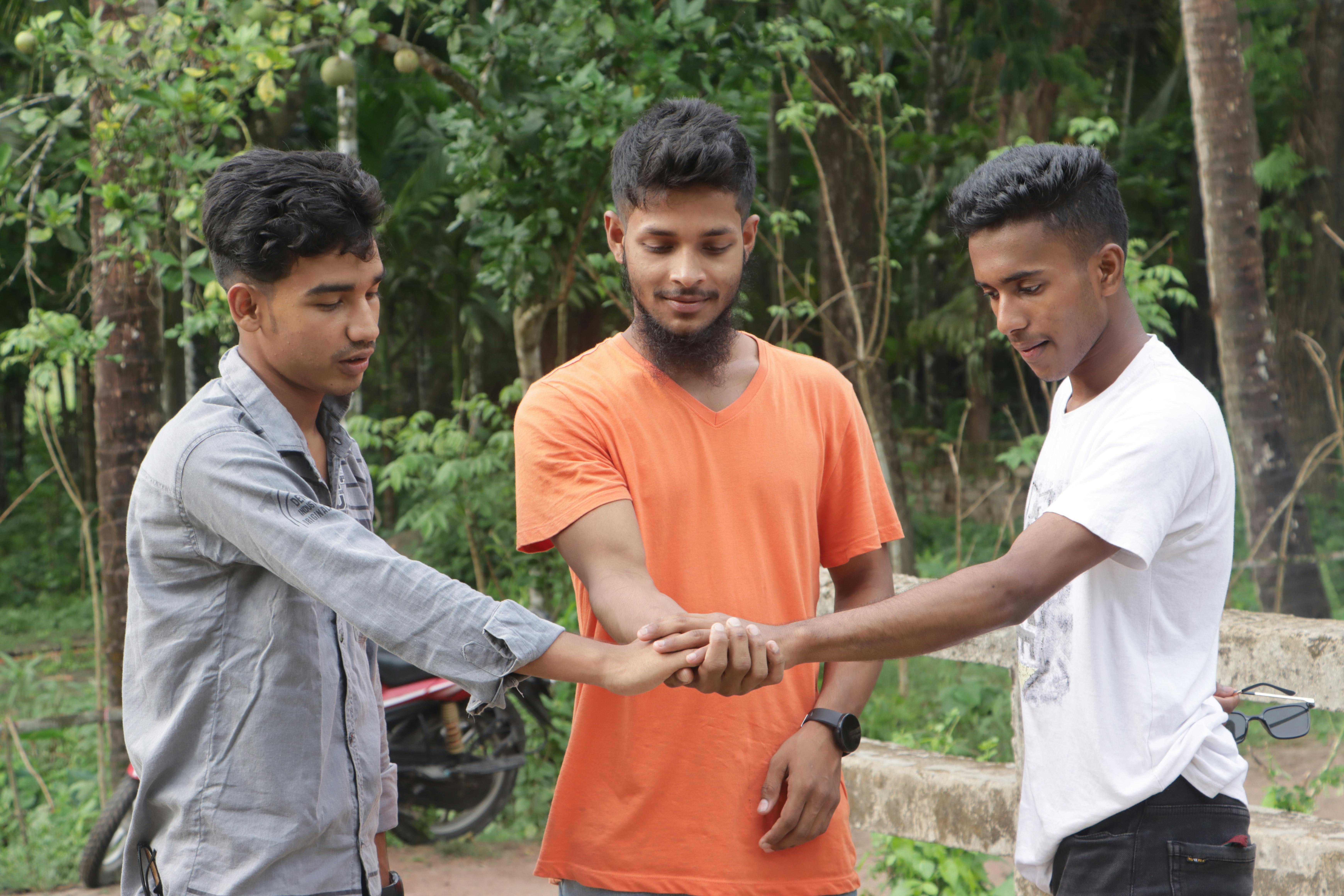 three young men standing outside and holding their hands in a huddle