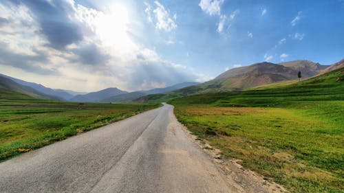 Landscape of a Road Through Fields and Mountains 