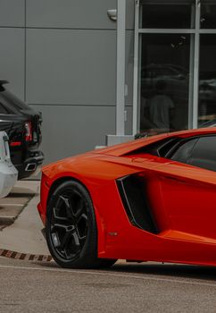 Close-up of a red sports car parked in an urban area, showcasing sleek design and luxury features.