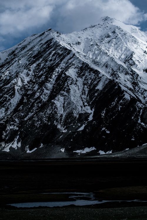 Free Stunning view of a snow-covered mountain peak under a dramatic cloudy sky, perfect for nature and travel themes. Stock Photo