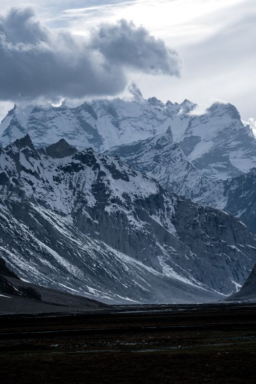 Free Captivating view of snow-capped mountains under a cloudy sky, showcasing nature's grandeur. Stock Photo