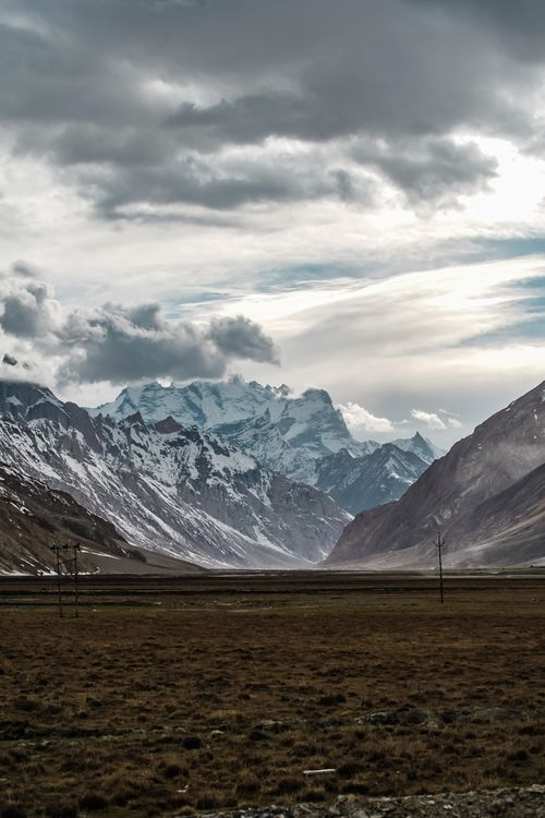 Free Scenic view of snow-capped mountains with cloudy sky, highlighting natural beauty and rugged terrain. Stock Photo