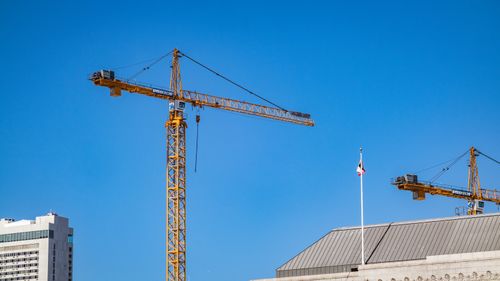 Free Tower cranes against a clear blue sky at an urban construction site. Stock Photo