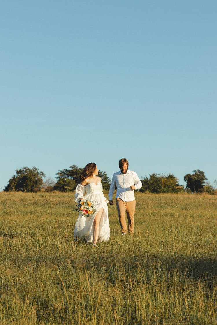 Woman And Man Running Through Grass Together