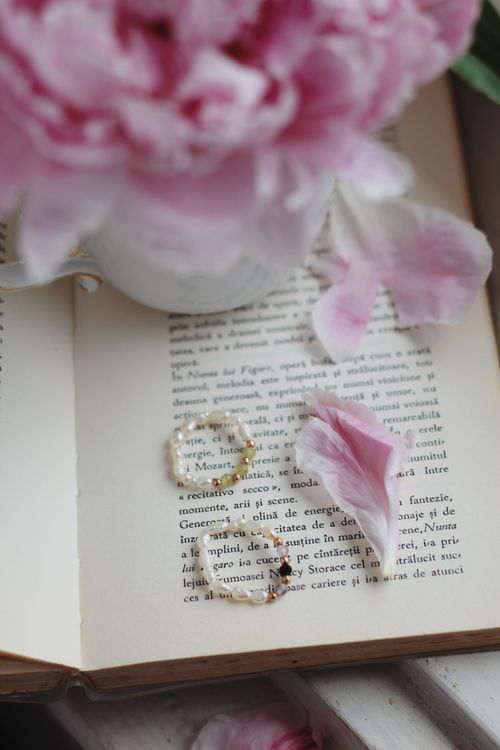 Free Open book with pink peony petals and beaded jewelry, creating a romantic and delicate atmosphere. Stock Photo