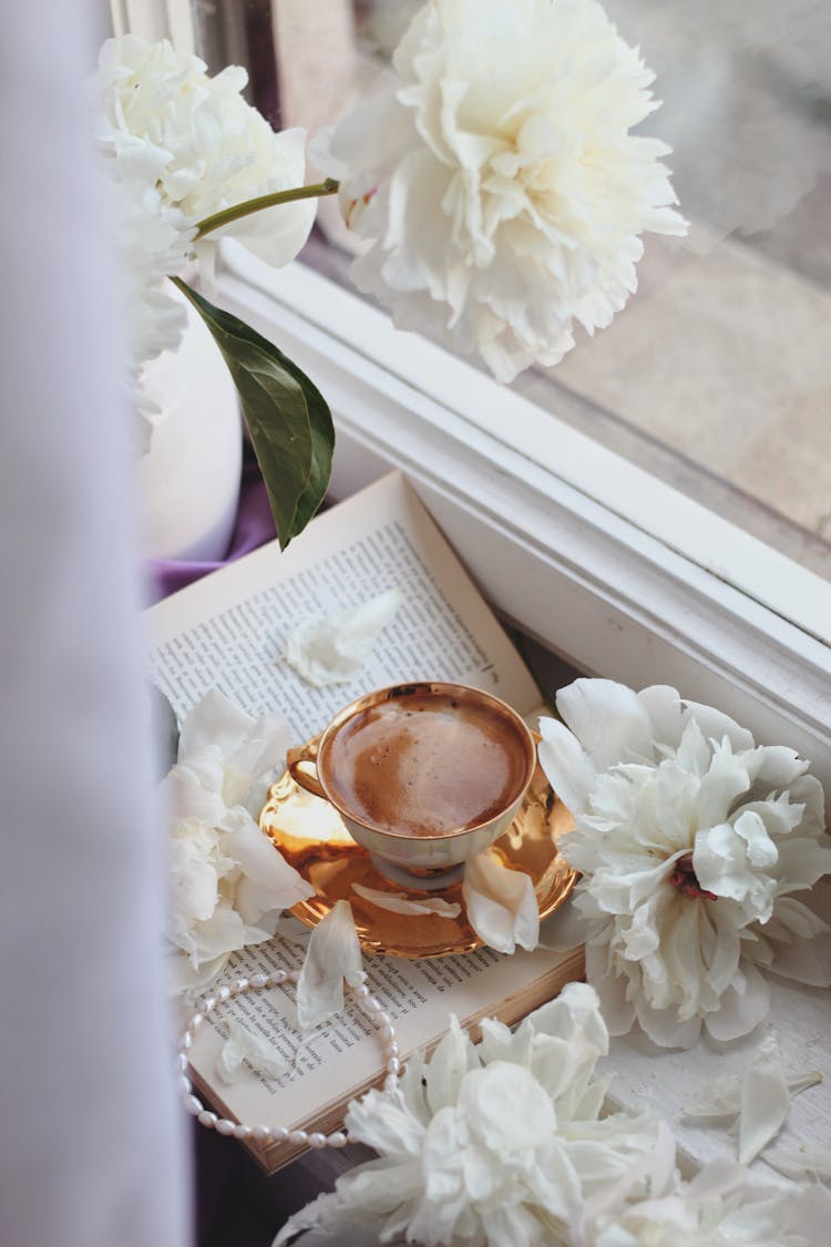 Coffee On Book And Flowers Near Window