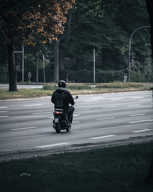 A Man in Black Jacket Riding Motorcycle on the Road