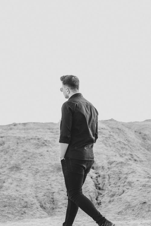 Grayscale Photo of a Man Walking with Hand inside Pocket