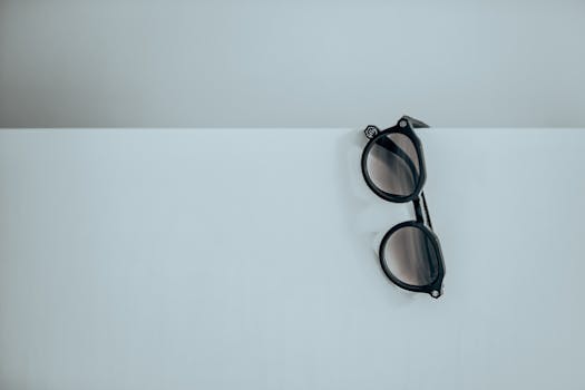 A minimalist photo of black sunglasses on a white surface with abundant copy space.