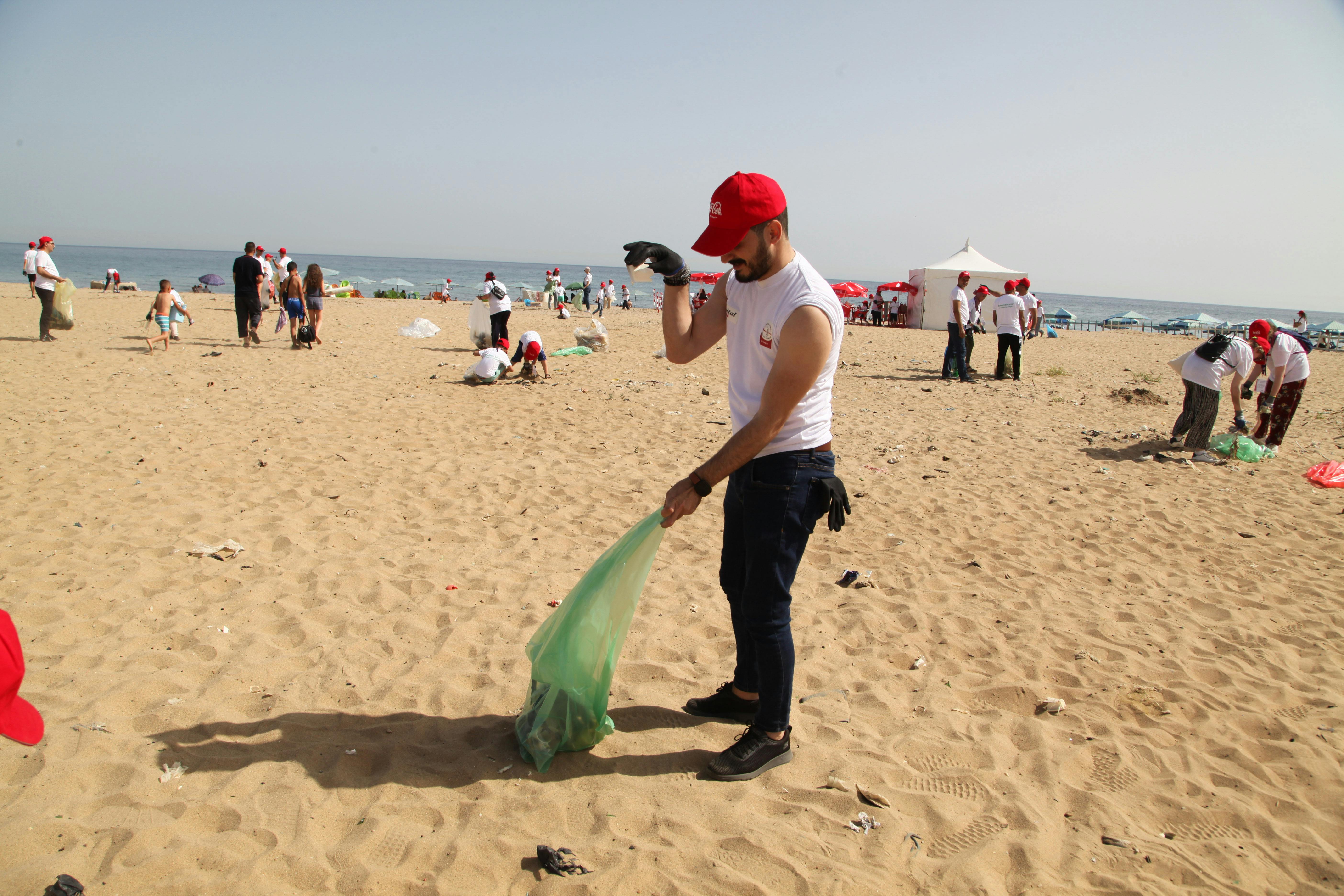 Volunteers cleaning up beach in Algiers, promoting environmental awareness.