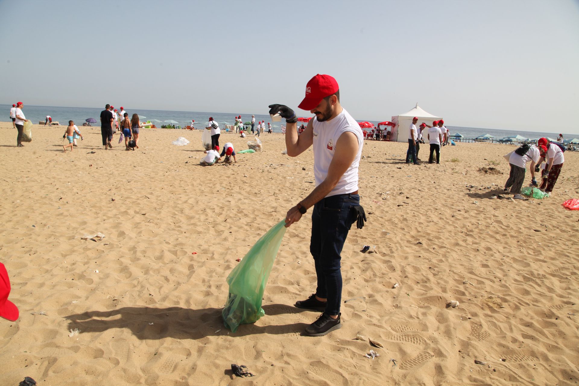 Volunteers cleaning up beach in Algiers, promoting environmental awareness.