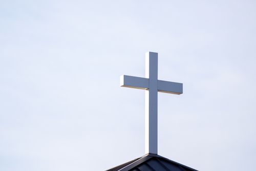 Free Minimalist image of a white cross on a church roof against a clear blue sky. Stock Photo