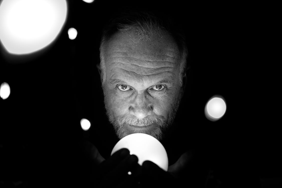 Grayscale Photo Of Man Holding Light