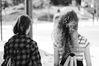 一张单色图像中，两个女人在户外行走，画面强调友谊与休闲风格