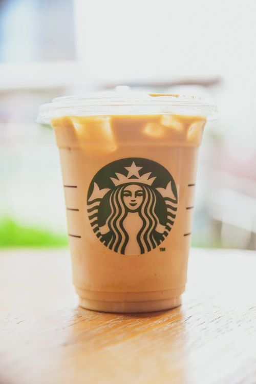 Free Close-up of iced coffee in a Starbucks plastic cup on a wooden table. Stock Photo