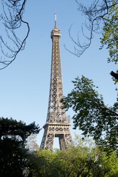 Vertical shot of the Eiffel Tower framed by spring foliage in Paris, France.