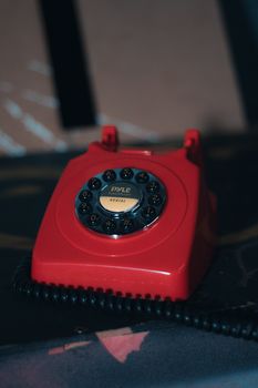 Close-up of a vintage red rotary phone with dial from PYLE brand, evoking nostalgia.