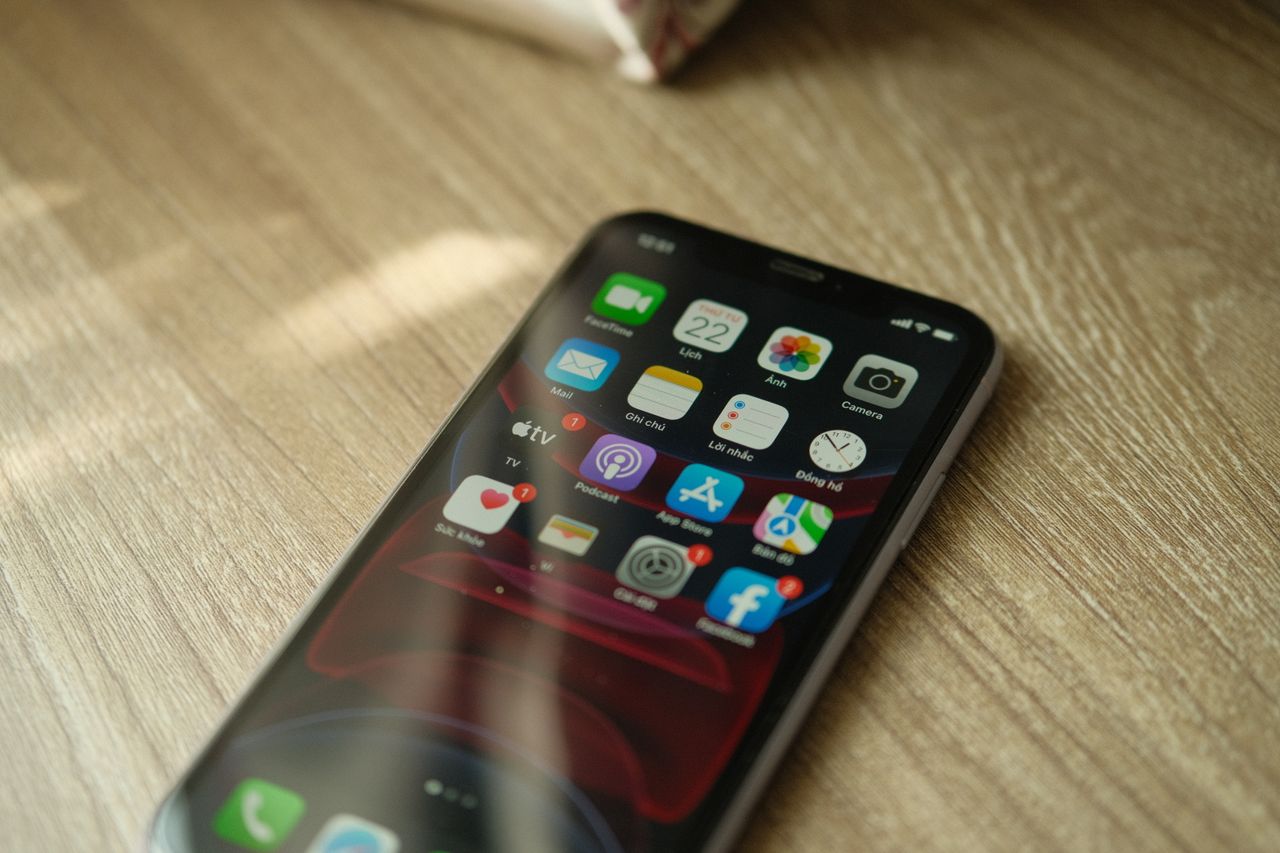 a close up view of a smartphone displaying various apps on a wooden su