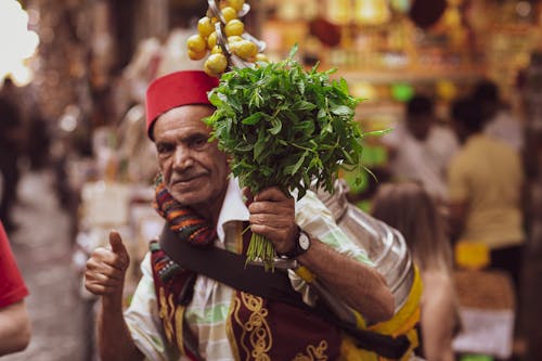Man on a Bazaar Holding a Bunch of Herbs 