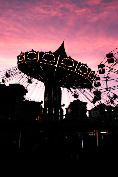Free Silhouette of a carousel against a dramatic sunset sky, capturing lively amusement park vibes. Stock Photo