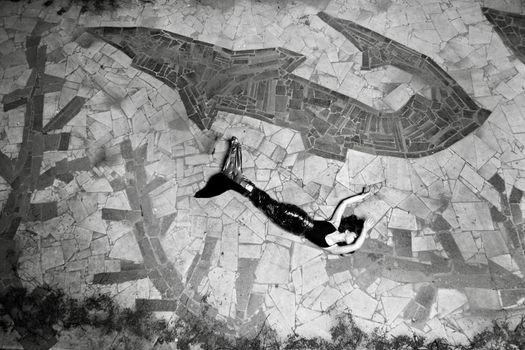 A woman in a mermaid costume lying on a mosaic stone pavement in Los Angeles.