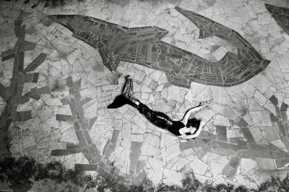A woman in a mermaid costume lying on a mosaic stone pavement in Los Angeles.