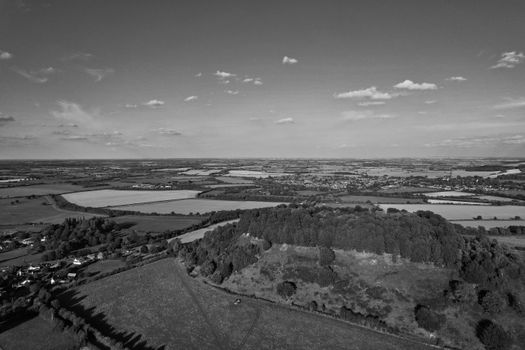 Black and white aerial view of Sharpenhoe, England, showcasing fields, forests, and distant villages.