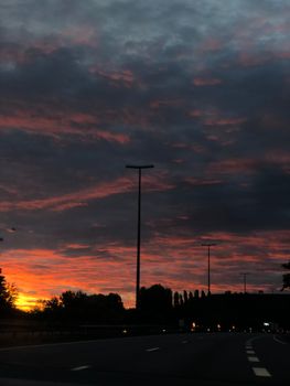 Silhouetted freeway at sunset with dramatic clouds in Noyelles-sous-Lens, France.