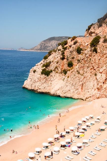 A stunning aerial view of a sunny beach in Antalya, Turkey showcasing turquoise waters and sunbathing tourists.