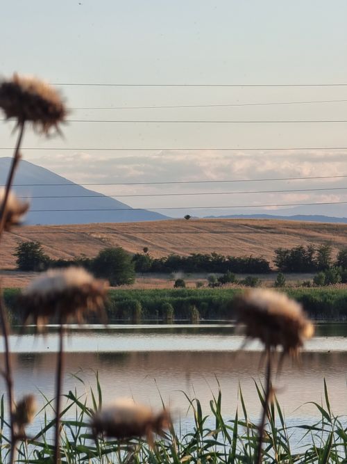 Free Serene rural landscape near Skopje with water, fields, and mountains in view. Stock Photo